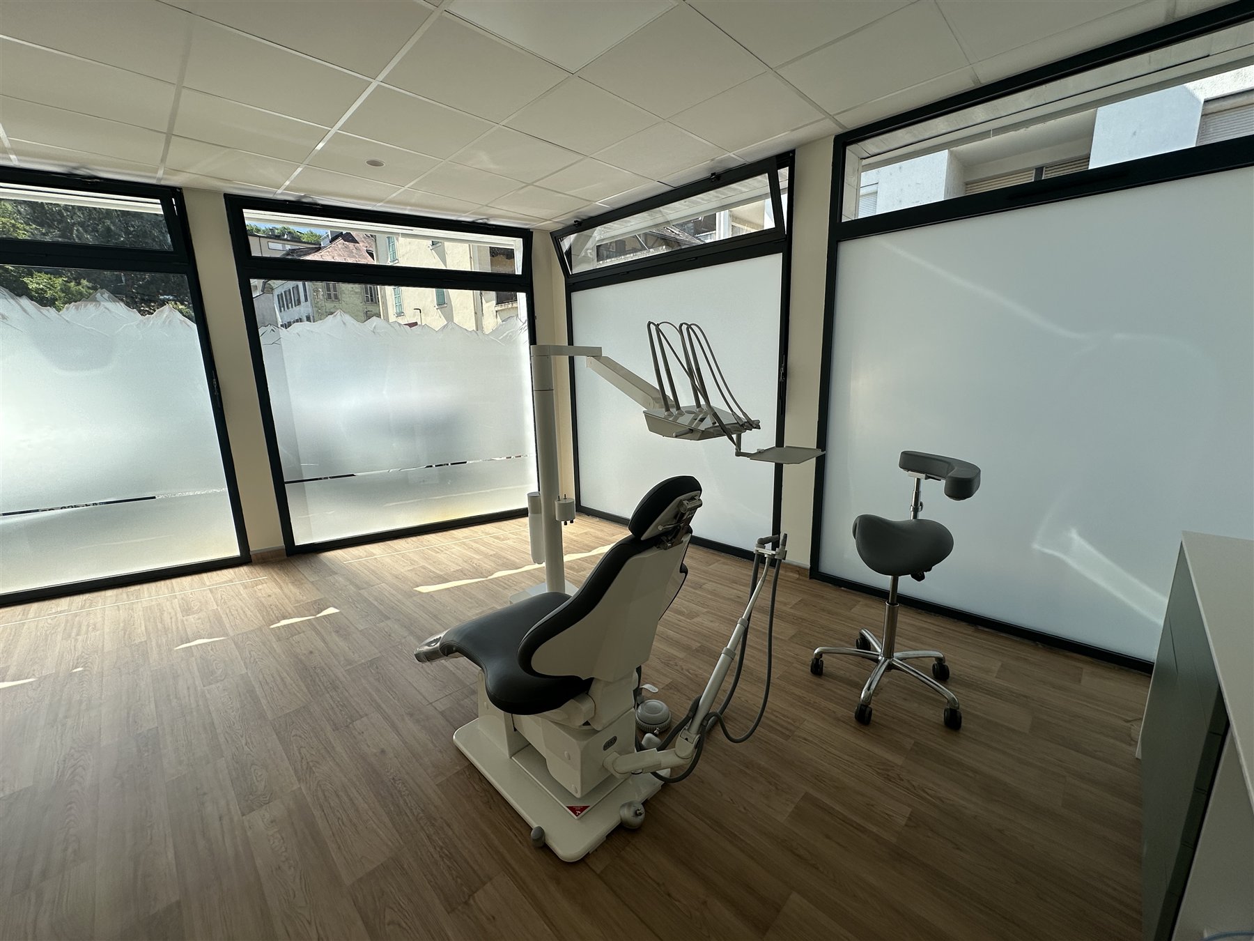 La salle de soins lumineuse du cabinet, avec son parquet en bois et ses grandes fenêtres